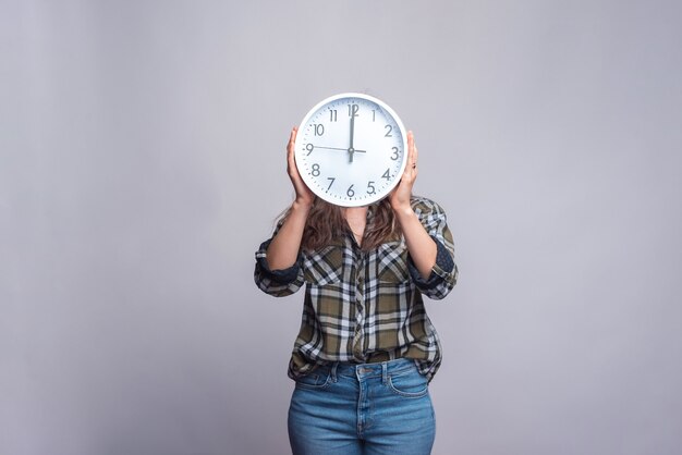 woman holding clock on hear head on white.