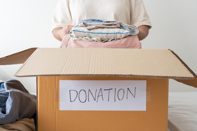 Woman holding clothes putting in a donation box Sharing Help Donation concept