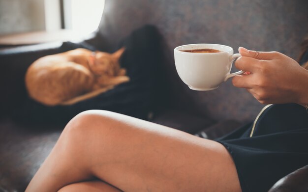 Woman holding coffee cup and a cat 