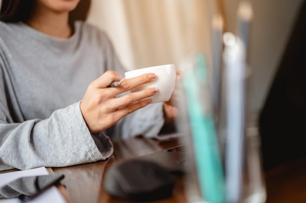 自宅でコーヒーカップの仕事をしている女性は、家ですぐに改善するために流行の状況を待ちます。コロナウイルス、covid-19、在宅勤務（WFH）、社会的距離、検疫、感染予防の概念。