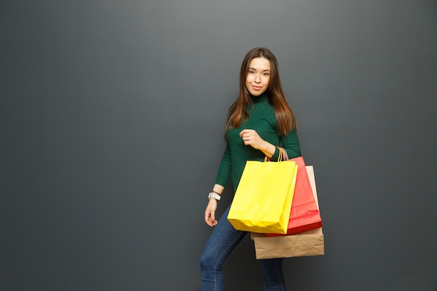 Woman holding colorful paper bags with purchases.