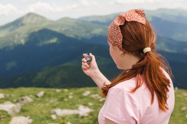 Woman holding a compass in hand on nature background, ready to travel, keep calm. Tourism, traveling, hiking and healthy lifestyle concept.