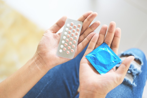 Woman holding contraception pills and condom