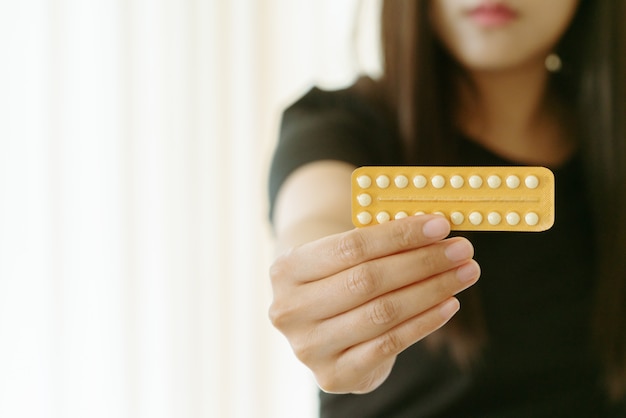 Woman holding contraception pills at home, closeup. Gynecology concept