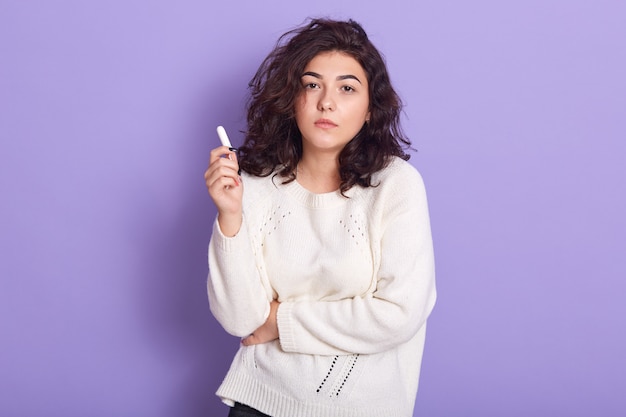 woman holding cotton tampon, has unhappy look, having monthly menstrual cycle, girl has period