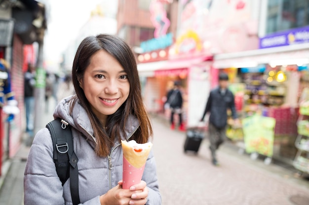 通りでクレープ ケーキを保持している女性