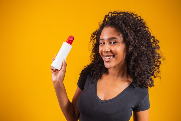 Woman holding a cream in yellow background