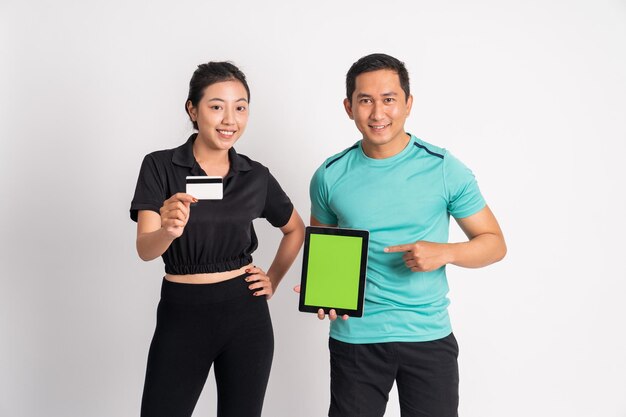 Photo woman holding credit card and man showing camera tablet screen on isolated background