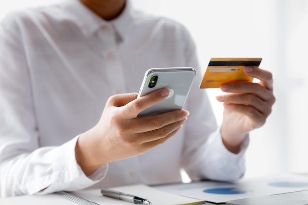 Woman holding a credit card she uses a credit card to pay for goods and services online the concept of using a credit card for online shopping ordering goods and services on the website