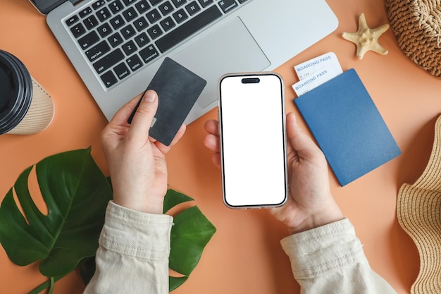 Woman holding credit card and smartphone buying plane tickets online top view