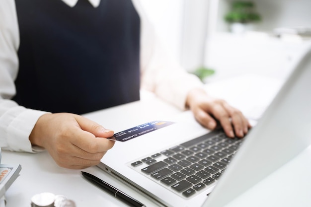 Woman holding credit card and using laptop computer for Internet online ecommerce shopping spending money Online shopping laptop technology concept Online shopping pay by credit card concept