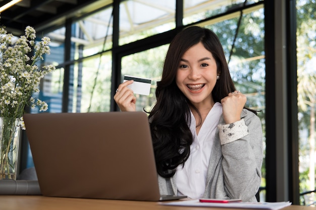 woman holding a credit card using laptop computer for online shopping