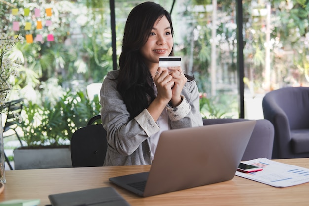 woman holding a credit card using laptop computer for online shopping