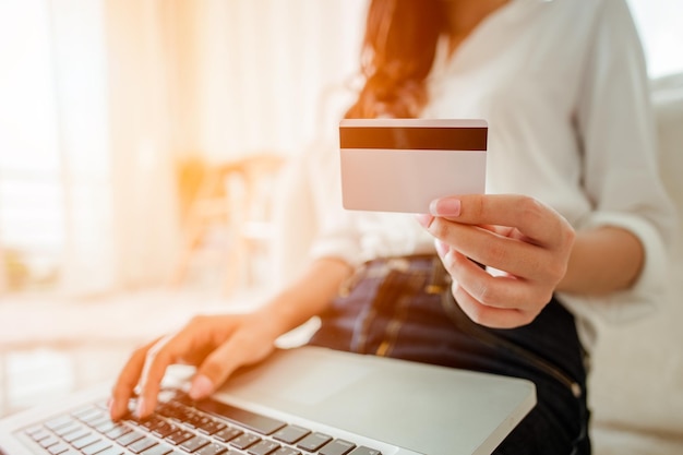 クレジットカードを持って、オンラインショッピングにラップトップを使用している女性。