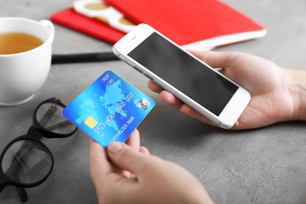 Woman holding credit card and using smart phone