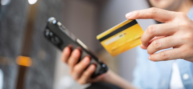 Donna che tiene la carta di credito e utilizza lo smartphone a casa imprenditrice shopping online e-commerce internet banking spendere soldi lavorando da casa concetto