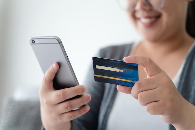 Photo woman holding credit card and using smartphone for online shopping internet banking spending money