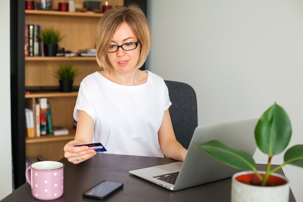 Photo woman holding a credit card while shopping online on the laptop