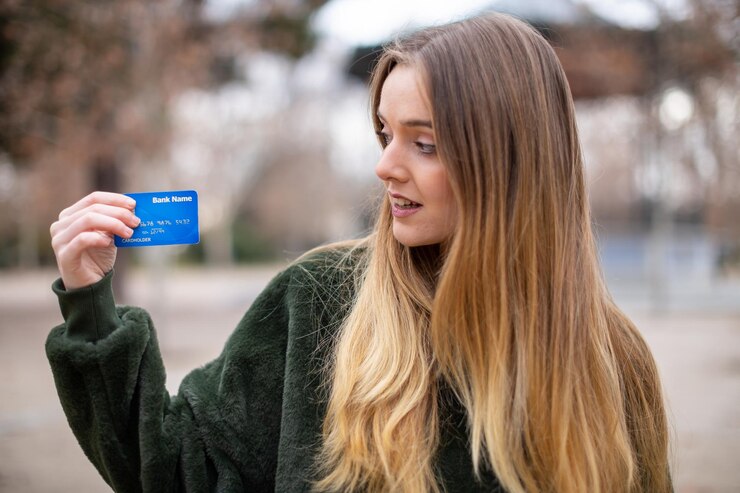 Photo woman holding credit card while standing in park
