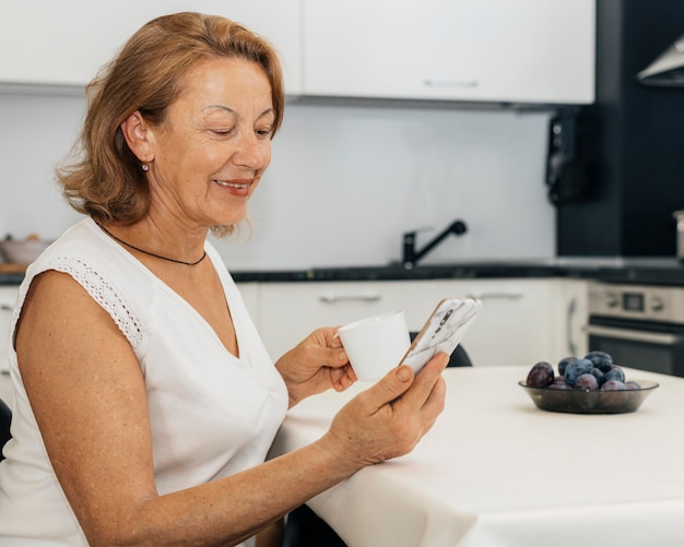 Foto donna che tiene una tazza di caffè e il suo telefono