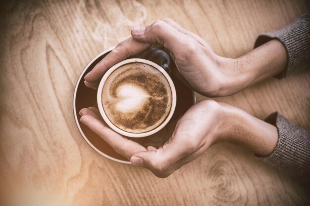 Woman holding cup of coffee on table