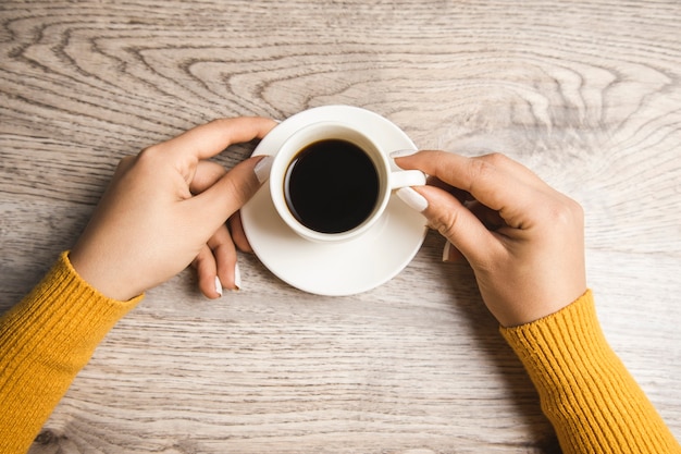 Woman holding cup of coffee on table