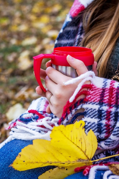 Donna che tiene una tazza nelle sue mani mentre all'aperto è coperta di coperta