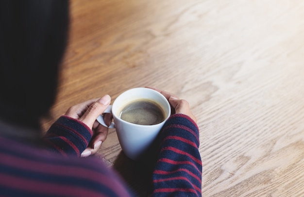 Woman holding a cup of hot coffee, winter season 