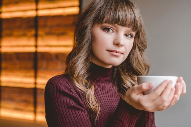 The woman holding a cup in the restaurant