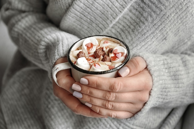 Woman holding cup of tasty cocoa with marshmallow, closeup