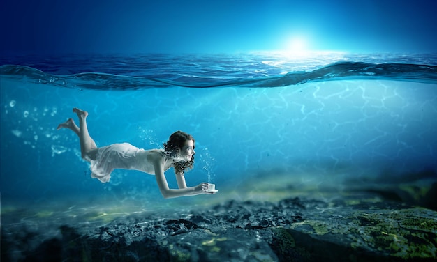 水中でカップを保持している女性。ミクストメディア