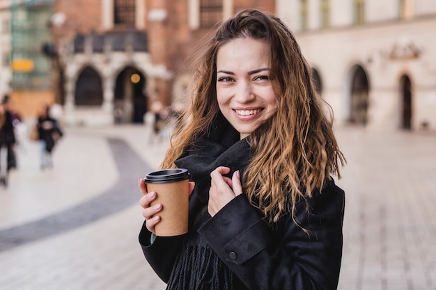 Woman holding cup on the urban background