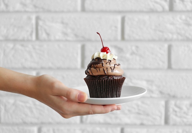 woman holding cupcake with berries on brick wall background