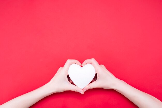 Woman holding decorative heart on red