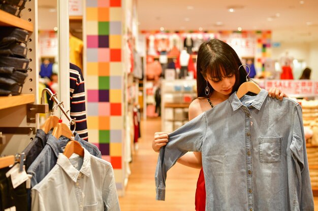 Photo woman holding denim shirt while standing in shop