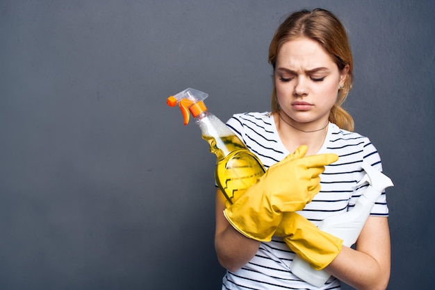 Женщина, держащая моющее средство в руках, уборка домашнего образа жизни сером фоне