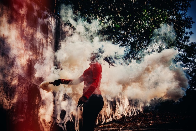 Foto donna che tiene una torcia di soccorso contro gli alberi