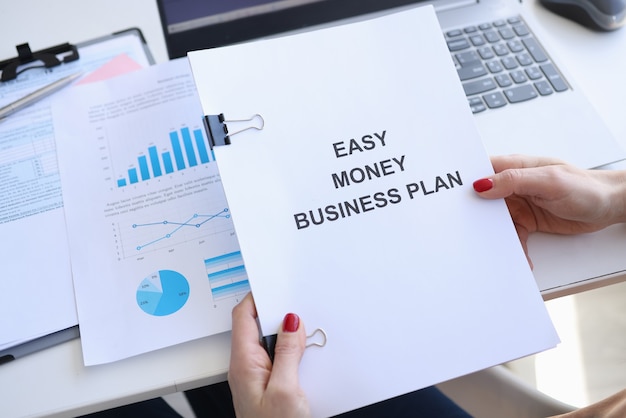 Woman holding documents with title easy money business plan in her hands closeup