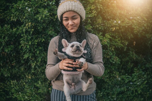 Photo woman holding dog during snowfall