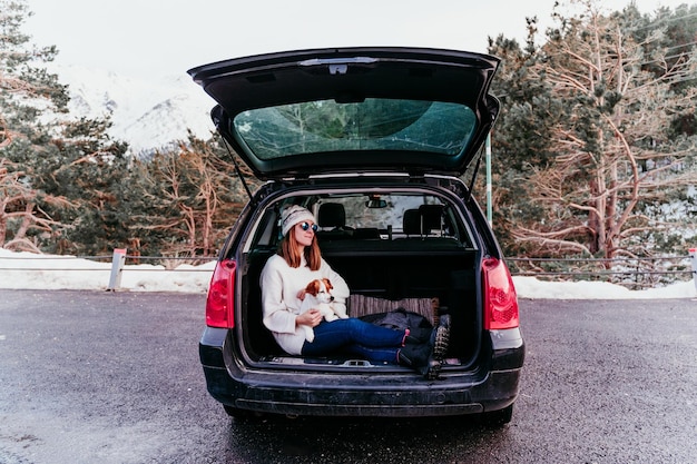 woman holding dog while sitting in car trunk