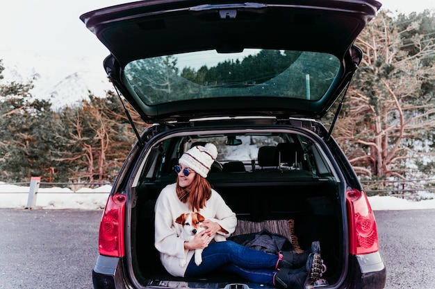 Photo woman holding dog while sitting in car trunk