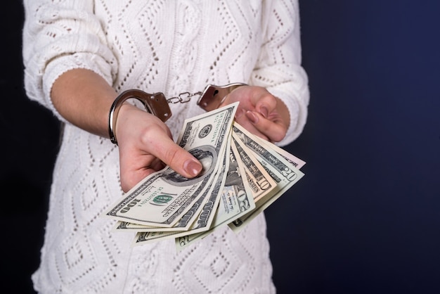 Woman holding dollar bills in handcuffs