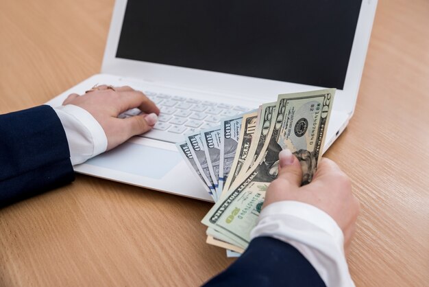 Woman holding dollar currency on white laptop