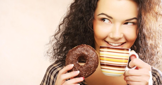 Woman holding donut and coffee in hand