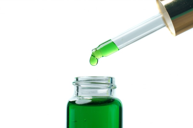 A woman holding a dropper with green hemp oil liquid. Laboratory concept.