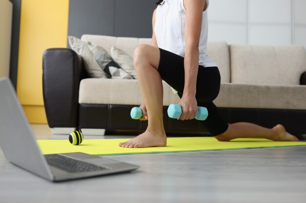 Woman holding dumbbells in front of laptop screen closeup