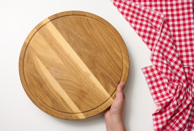 Woman holding empty round wooden pizza board in hand, body on a white background, top view