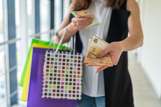 Woman holding european banknotes and colour shoping bags at supermarket. black friday. discount concept