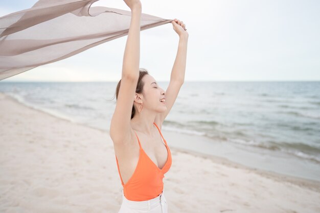 Donna che mantiene tessuto al vento in una vacanza vacanza in spiaggia