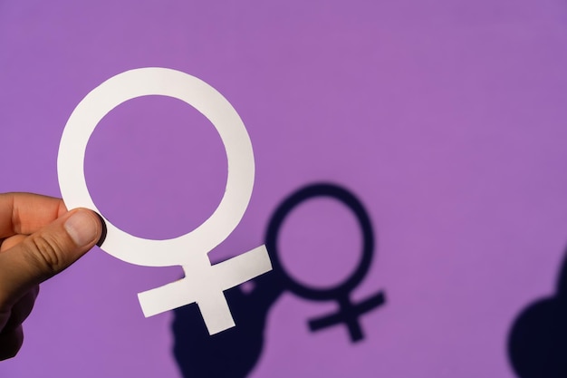 A woman holding the female symbol on a purple background and her beautiful shadow is seen, march for women's rights and equality, with spring shadow